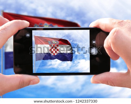 The hands of men make a phone photograph of the flag of Croatia.