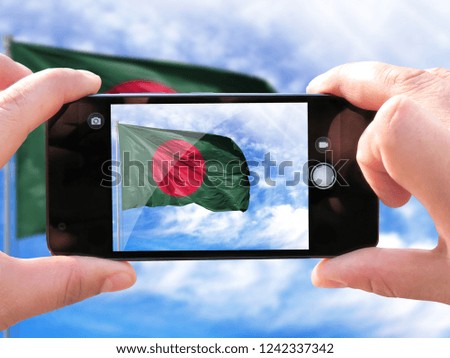 The hands of men make a phone photograph of the flag of Bangladesh.
