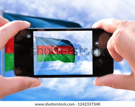 The hands of men make a phone photograph of the flag of Azerbaijan.