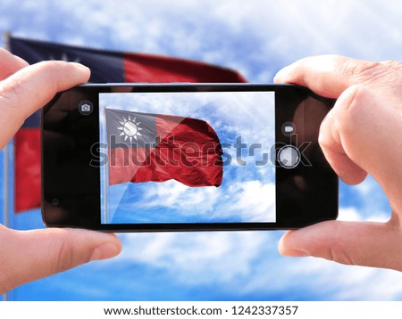 The hands of men make a phone photograph of the flag of Taiwan.