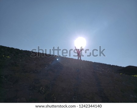 silhouette of a man raising his arms under the sun, backlit photo