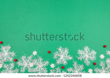 Creative Christmas layout. Snowflakes on green background whit copy space. Border arrangement. Flat lay top view.