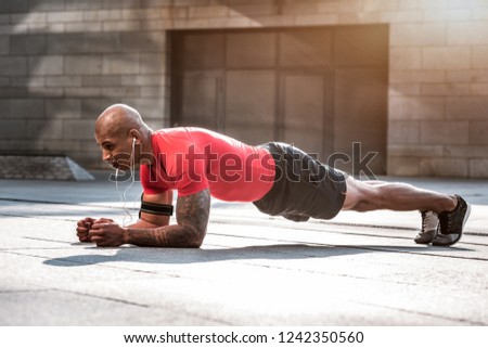 Training plan. Strong hard working sportsman doing pushups while having a workout