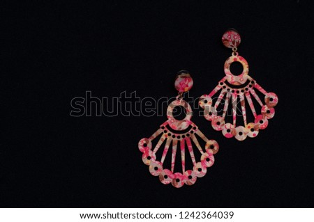 Earring jewelery pink color, photo on black background.