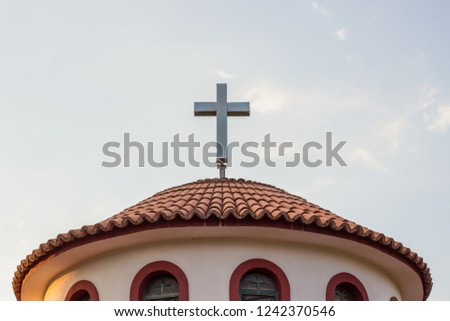 catholic religion cross on roof of small chapel building on sky background, copy space