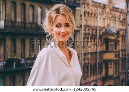 Portrait of a beautiful girl in a bathrobe in the morning against the background of the house