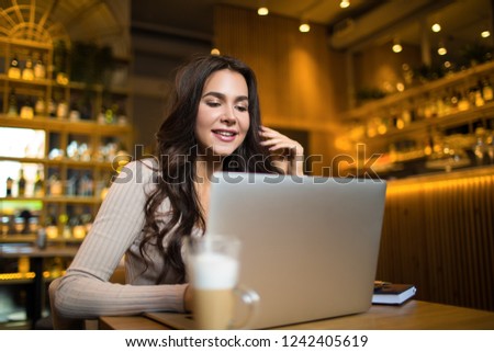 Luxurious beautiful smiling woman successful business worker having online video conference via modern laptop computer while sitting in restaurant. Cheerful female talking via web cam call on notebook