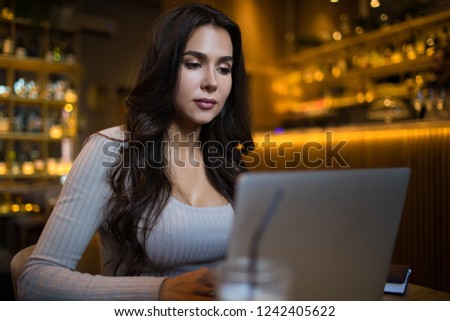 Attractive woman professional real estate analyst working on laptop computer while sitting in modern restaurant interior. Female skilled fashion blogger typing article on notebook, relaxing in cafe