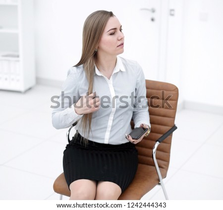 young business woman with smartphone sitting on an office chair