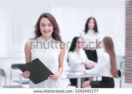 successful young business woman with clipboard in the background of the office