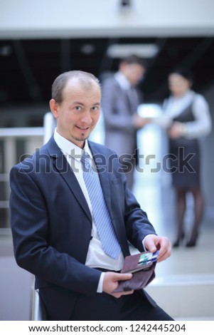 happy businessman opens wallet.photo on the background of office
