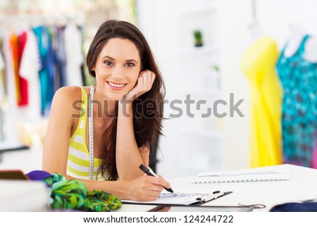 attractive young female dressmaker sketching in studio