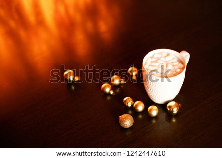 White mug with hot chocolate and marshmallows on the dark brown table and background with golden bokeh. Christmas holiday concept, free space for text.