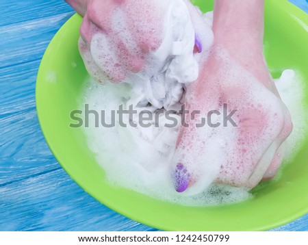 hands washing clothes in a basin on a wooden background