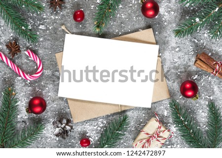christmas greeting card in frame made of fir branches, star anise, decorations and pine cones on stone background covered with snow. Xmas background. mock up. Flat lay. top view with copy space