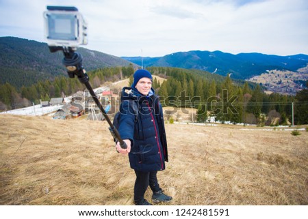Happy tourist man hiking in mountains and take selfie on action camera
