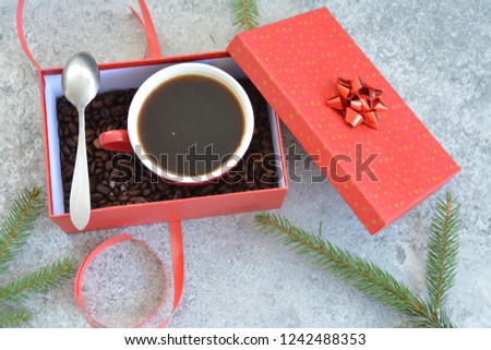 A cup full of coffee is in a Christmas gift box with coffee beans in it - coffee as a treat and gift for Christmas nicely packaged