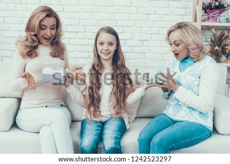 Daughter Giving Gift Boxes to Family at Home. Mother with Daughter. Smiling Women. Celebration Concept. Happy Family. Sitting at Home. Holiday in March. White Sofa. Happy Grandmother.