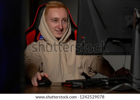 Professional cyber sportman trains for the championship. Male hooded gamer playing online game on pc computer Gaming Club.
