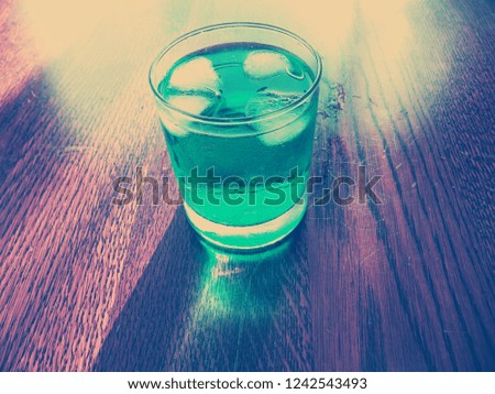Sweet cold refreshing green cocktail drink with ice. This drink contains alcohol. There is condensation on the glass.