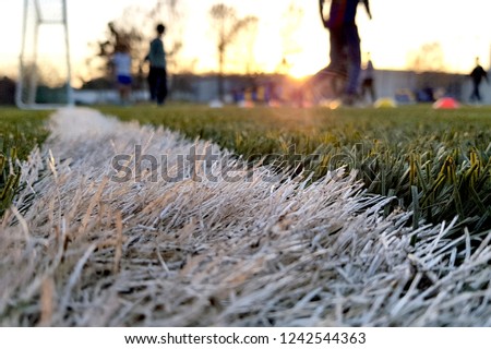 Close the artificial lawn with a white stripe and blurred football against the background.