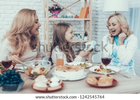 Family Celebrating Grandmother's Birthday at Home. Cake on Table. Happy Family. Mother with Daughter. Smiling Women. Smiling Grandmother. Celebration Concept. Glass of Wine. Giving Gift Box.