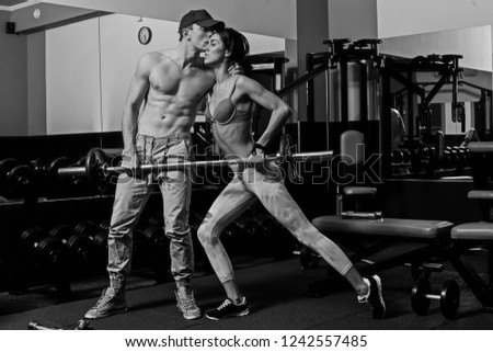 A picture of a couple standing in the sport club's training room together and showing their big thumb's up. They are happy to exsercise in this fitness club. 