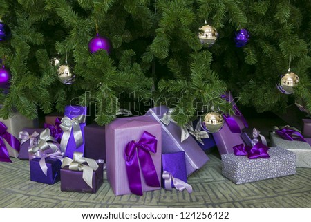 Photo of luxury gift boxes under Christmas tree, New Year home decorations,  wrapping of Santa presents, festive fir tree decorated with garland, baubles and angels, traditional celebration