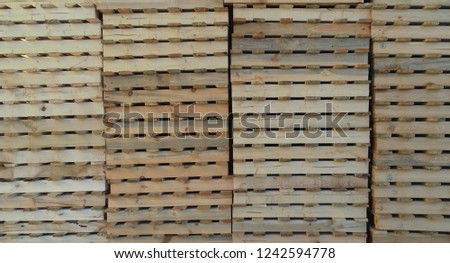 side view of a lot of yellow pallets standing on top of each other in a row in several columns