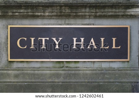 Brass City Hall sign on a stone wall