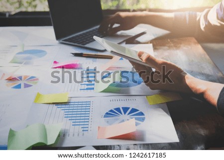 Business research data stock concept, Asian businessmans using tablet and laptop computer of digital to analysis graph infomation diagram on wooden desk in office.