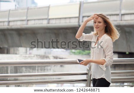 Young beautiful happy woman using smart phone on city background