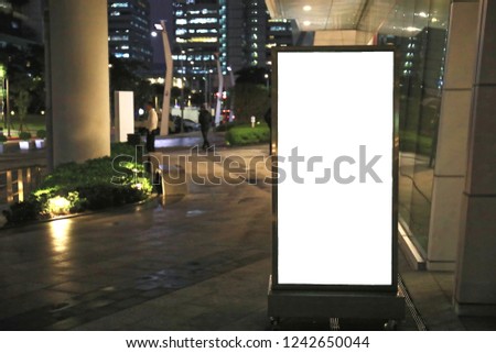 The blank advertising board is put aside the pavement in a city at night.