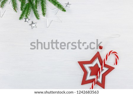 christmas holiday background with green fir tree branch, decorative wooden and glass stars and red candy cane. top view with copy space