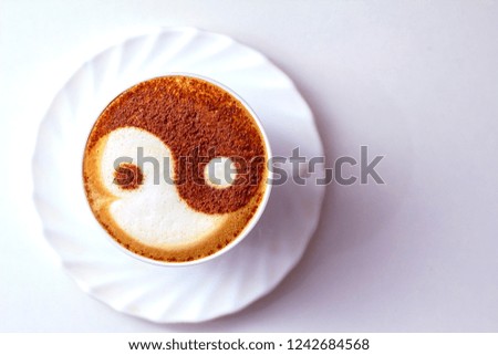 a cup of cappuccino coffee with a yin and yan cinnamon symbol pattern on milk foam