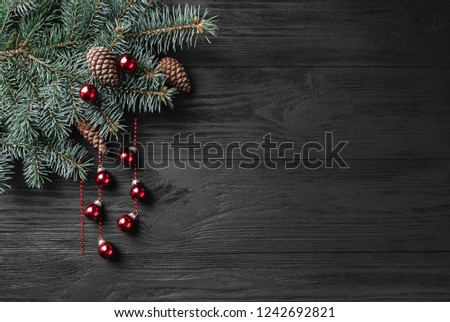 Holiday Christmas background with spruce branch on a dark wood table. Xmas and happy new year greeting card. Copy space. View from above. Flat location, place for text.