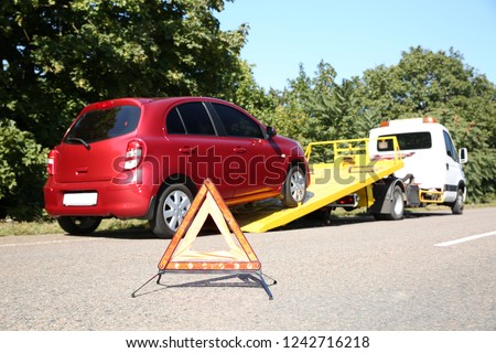 Emergency stop sign with broken car and tow truck on background