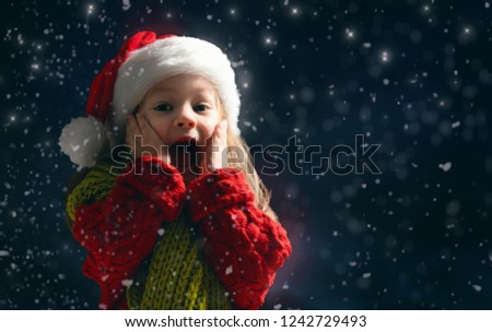 Merry Christmas and happy holidays! Little girl with snow. Child enjoying the game outdoors. Portrait kid on dark background.