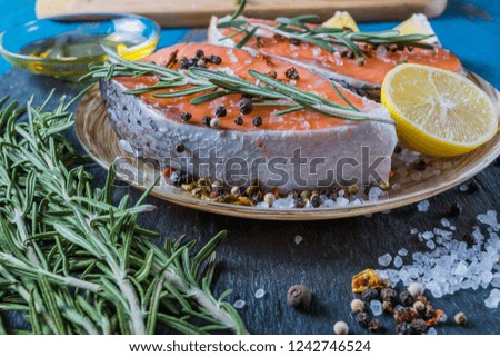 salmon fish on a plate with spices, olive oil and lemon before cooking, flat lay.
