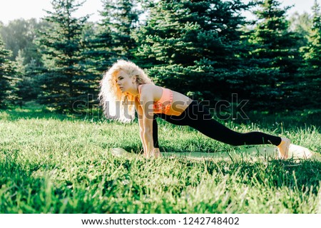 Image of young curly-haired sports woman practicing yoga on rug 