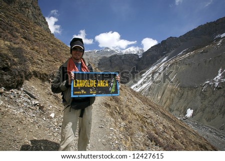 man holding a landslide warning sign, annapurna, nepal