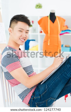 Asian boy sitting on the chair with the sketch-board