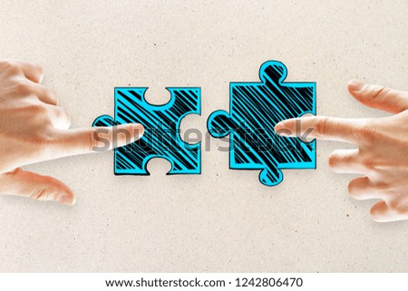 Hands with drawn puzzle pieces on concrete background. Teamwork and game concept 