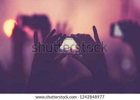 Young fan girl shoots video with phone on concert in nightclub.Woman take pictures with smartphone on entertainment event in music hall.Festival,musical party audience film festival with mobile camera