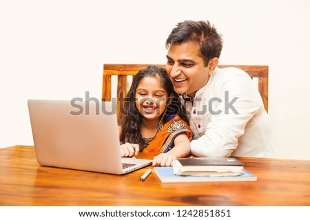 Indian father and daughter using laptop computer at home