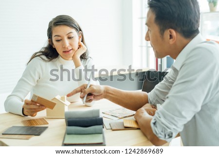 Young asian happiness couple love family male and female talking about house purchase discussing a choice with home plan, real estate and family house concept.house design ideas with sample material.