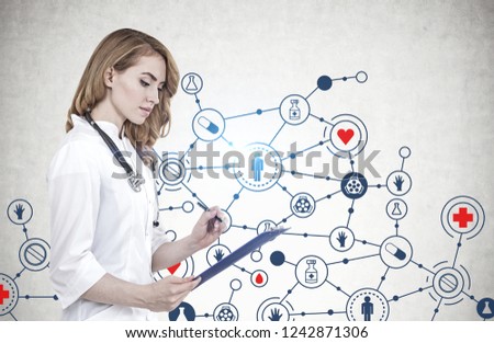 Beautiful woman doctor with red hair and clipboard standing near concrete wall with medical sketch drawn on it. Toned image