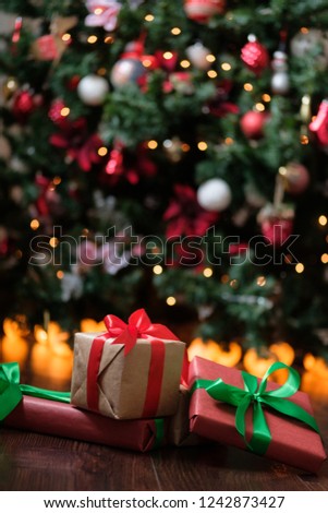 Gifts lie under the tree with a glowing gerland on a dark wooden floor