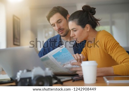  Attractive couple planning their trip looking at map at home                              