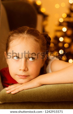 Little girl with her bear toy, waiting for Santa Claus. Christmas bokeh lights. Winter holidays. 